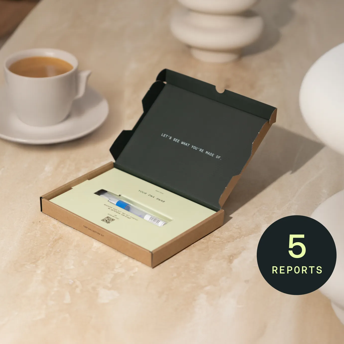 Open box containing a DNA swab with a coffee cup and saucer in the background