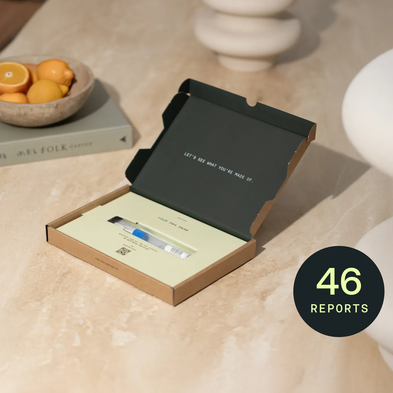 DNA Kit in an open box on a table with oranges and books in the background.
